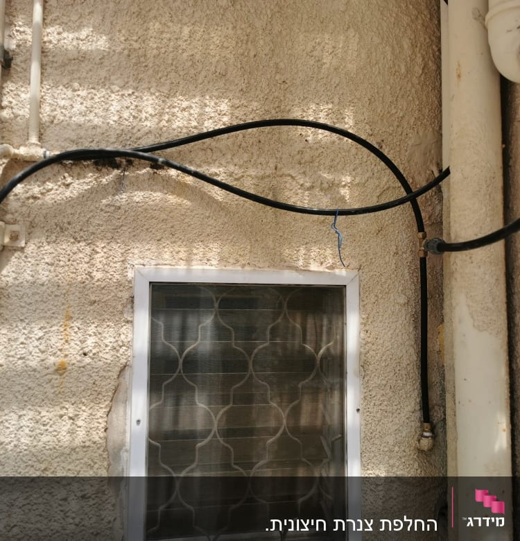 צינורות שחורים מחוברים לקיר חיצוני ליד חלון